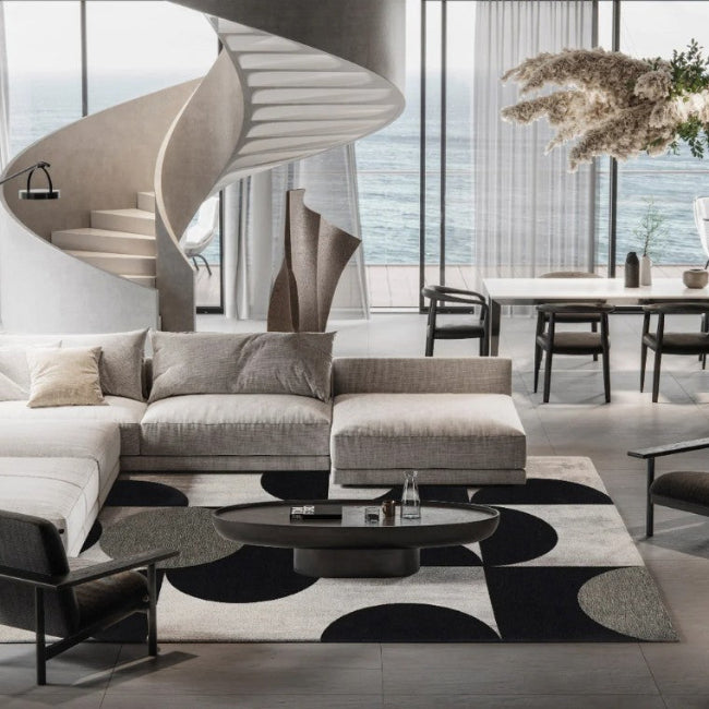 Modern living room with a sectional sofa, chairs, and a dining area with ocean view.