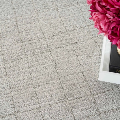 Close-up of a textured beige luxury rug with subtle grid pattern from Nourison Andes Rug Collection next to pink flowers