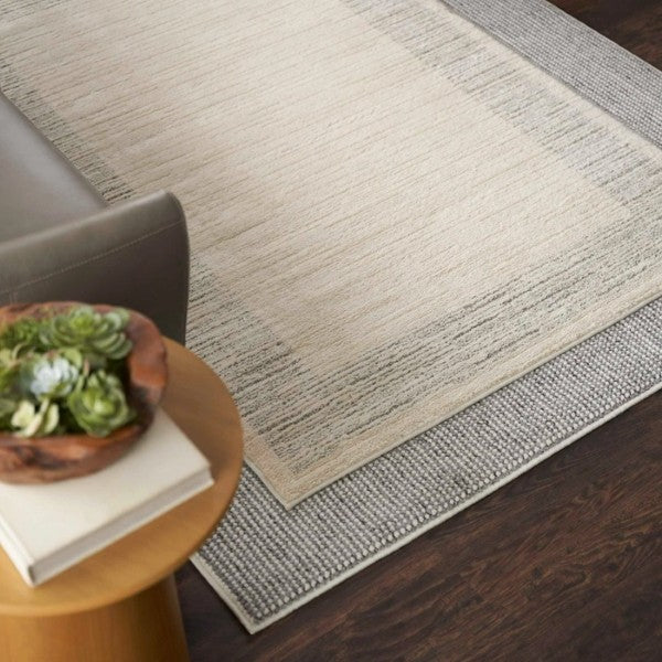 Luxury Nourison Andes Rug Collection in neutral tones layered on dark wooden floor beside a sofa and wooden side table