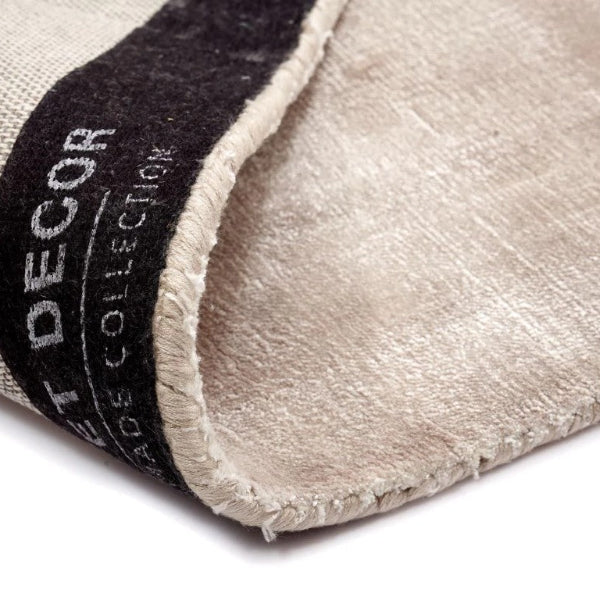 Close-up of a beige rug with a black border and 'Decor' branding.