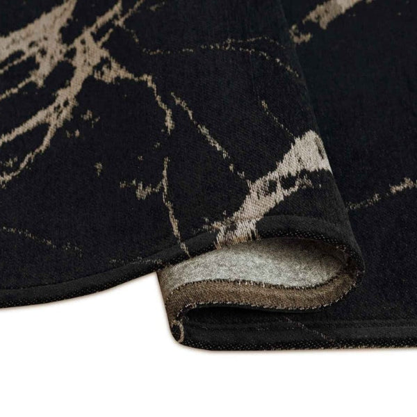 Close-up of a black and gray patterned rug corner on a white background