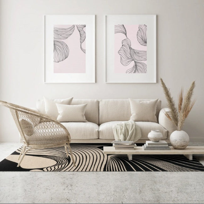 Modern living room with a beige sofa, wicker chair, and abstract wall art.