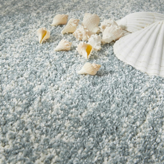 Close-up of light blue carpet with seashells on a textured surface