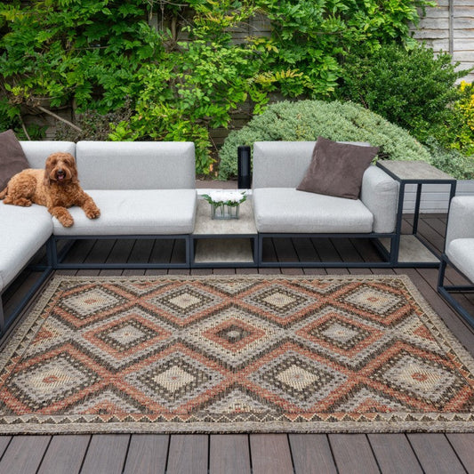 Sumac Outdoor Rug Collection displayed in a stylish patio setting with modern furniture and a dog