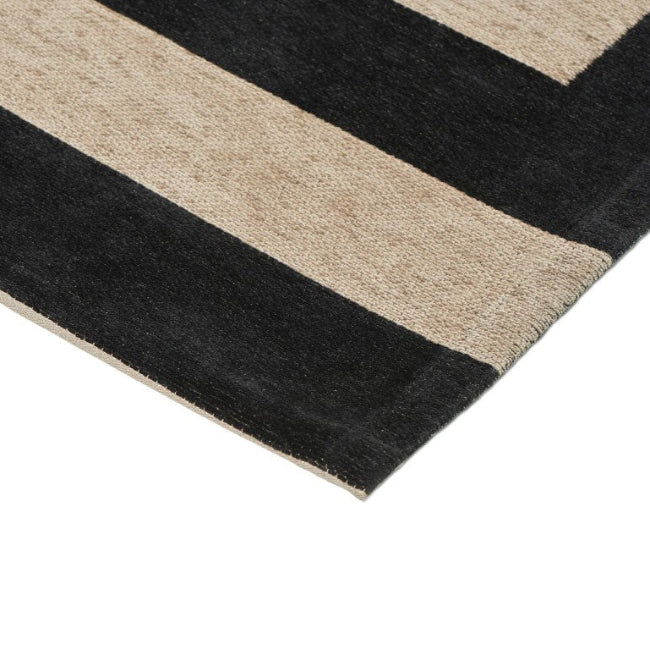 Close-up of a black and beige striped rug corner on a white background