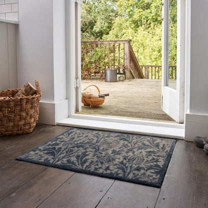 Turtle Mats Thistle Design indoor Mat with blue and grey floral pattern placed by an open door on wooden floor