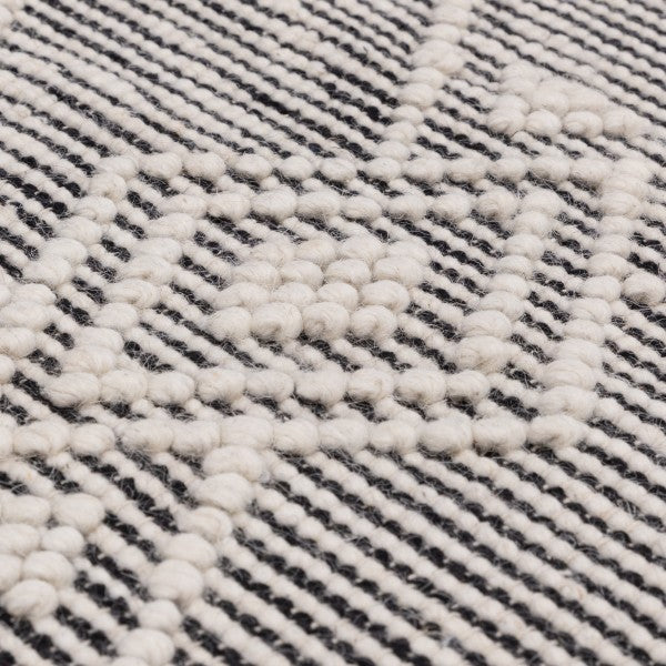 Close-up of Asiatic Boho Collection Asra Rug showcasing textured white patterns on a striped black and white background
