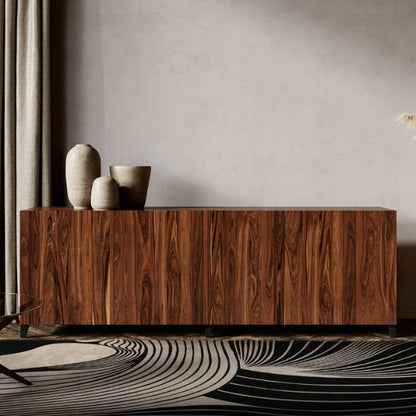 Wooden sideboard in a modern living room with decorative items and a patterned rug.