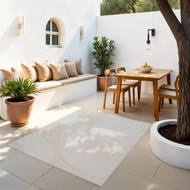 Outdoor patio with white walls, wooden furniture, and potted plants