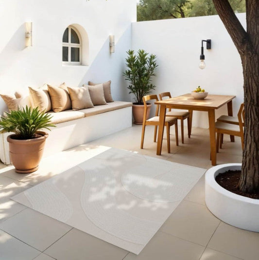 Outdoor patio with white walls, wooden furniture, and potted plants